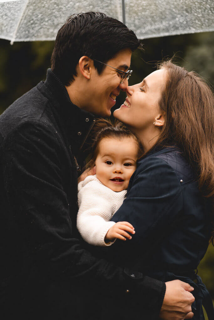 Family portrait happy parents kissing Queen elizabeth park
