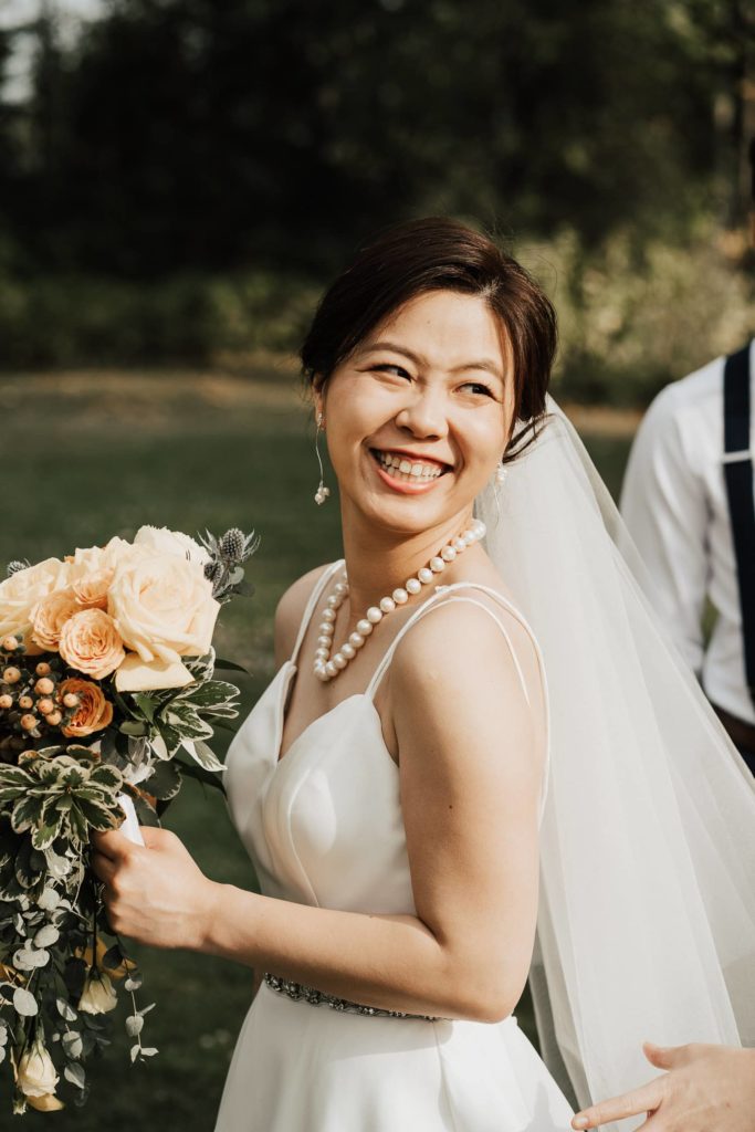 Bride smiling with her bouquet at wedding party session in vancouver park