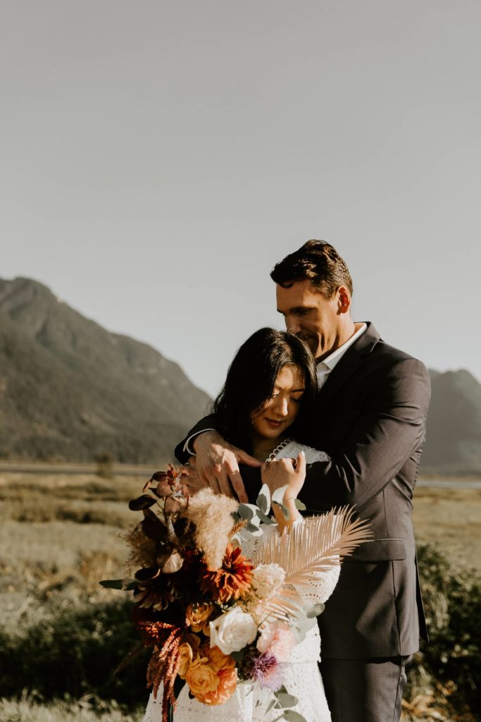 bride and groom wrapping the bride with the wedding bouquet at pitt lake