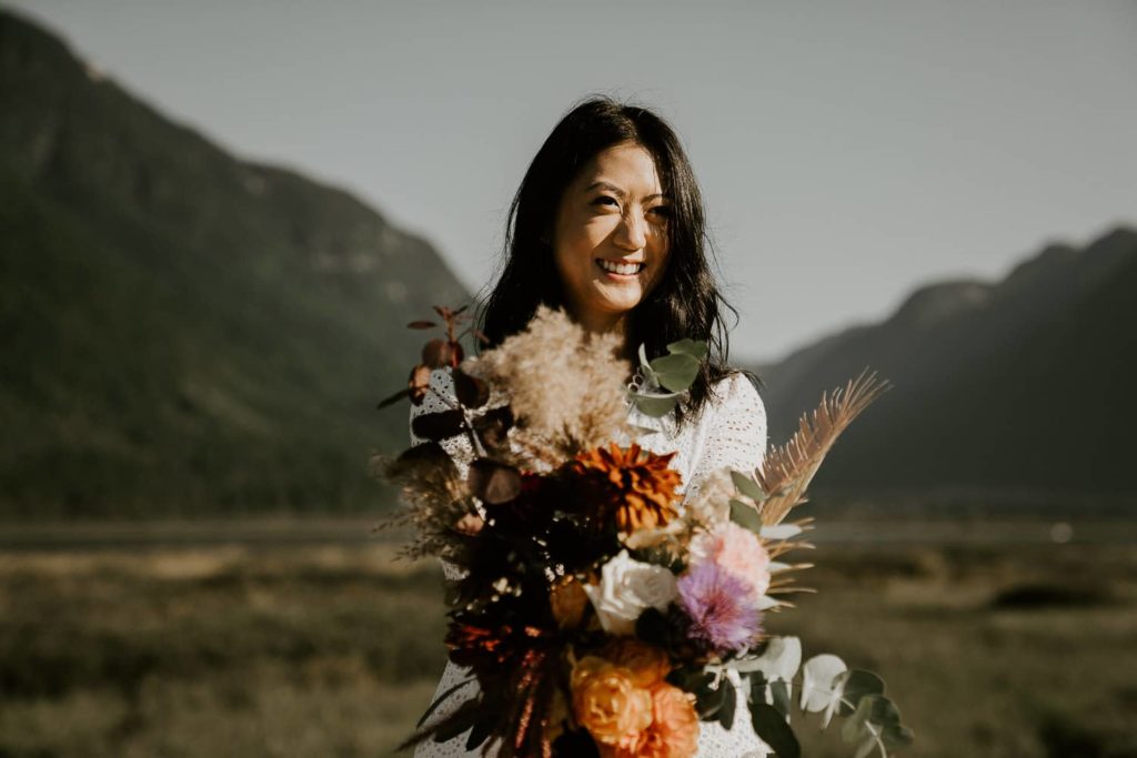 bride holding her wedding bouquet at pitt lake and smiling