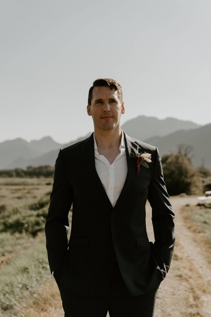 groom hands pockets with serious face at pitt lake