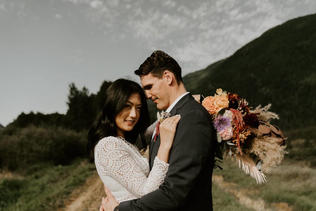 groom holding bride with wedding bouquet at pitt lake
