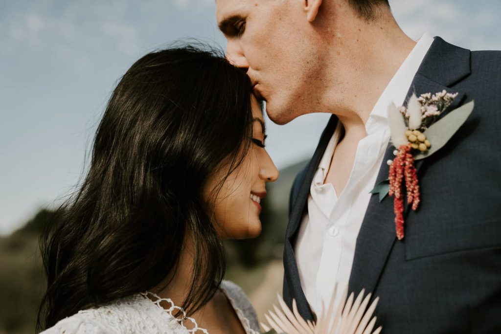 groom kissing bride forehead at pitt lake