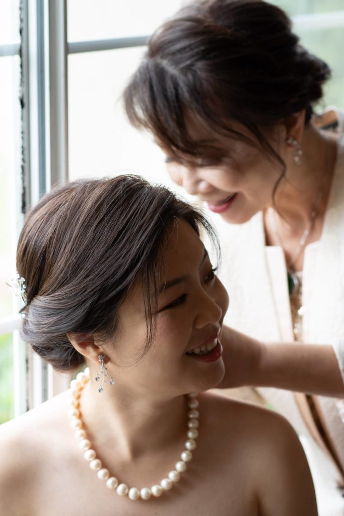 Mom adjusting necklace of her bride and daughter before the Chinese tea ceremony