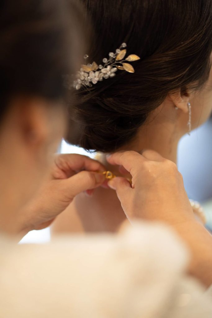 Mom adjusting pearls necklace of her daughter bride before Chinese tea ceremony